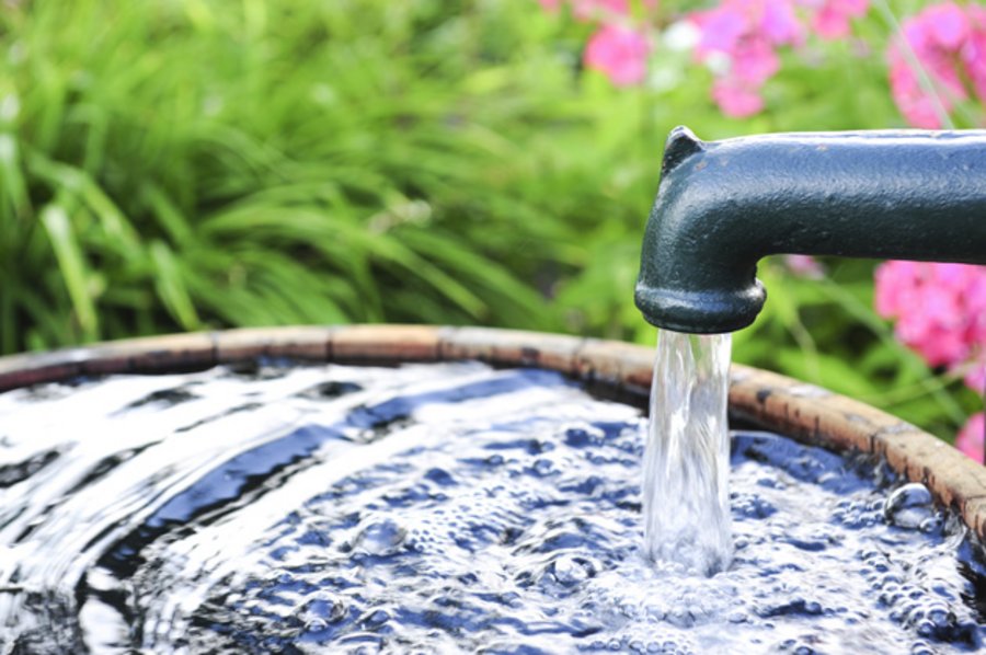 Wasser fließt in einen Garten-Bottich.