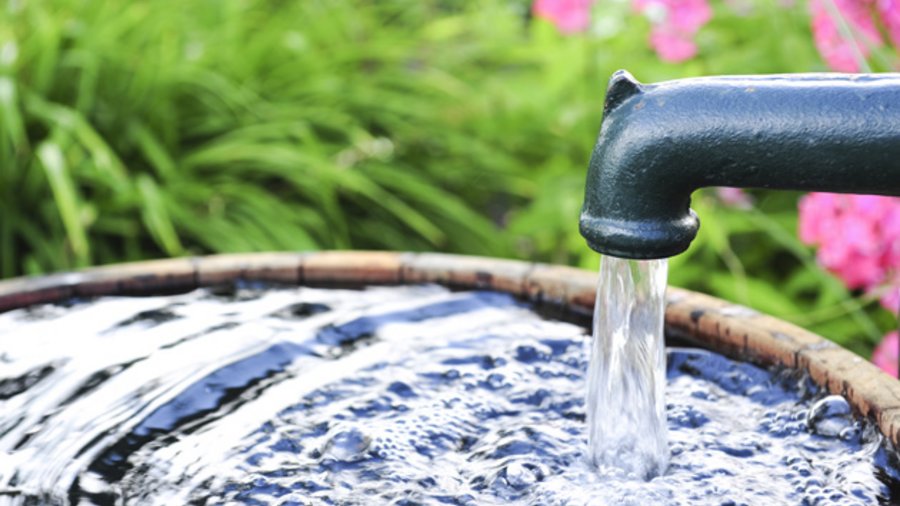 Wasser fließt in einen Garten-Bottich.