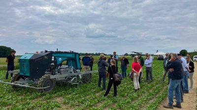 Roboter und Personengruppe auf Zuckerrübenfeld
