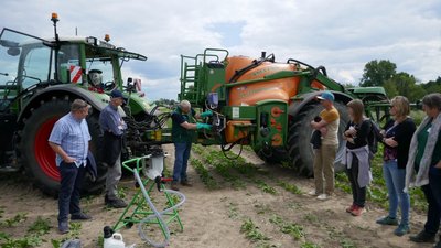Personengruppe an einem Traktor mit Anhängespritze