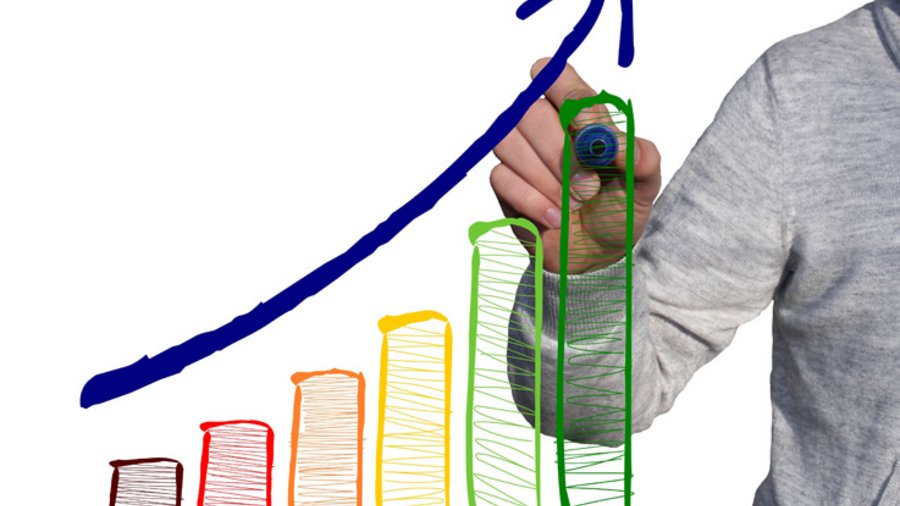 Ein Mann zeichnet ein Balkendiagramm und einen Pfeil der nach oben zeigt.